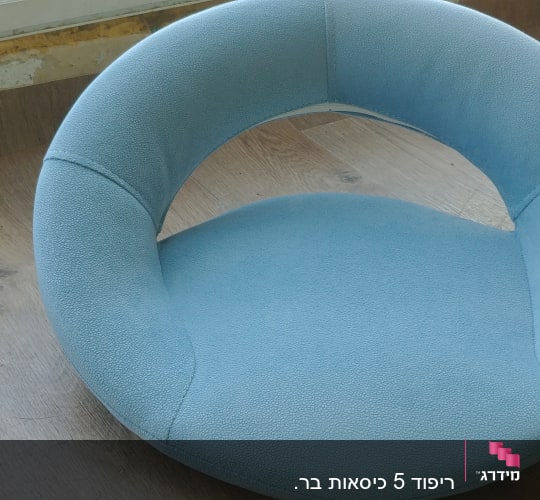 כרית עגולה מרופדת בצבע תכלת על שולחן עץ